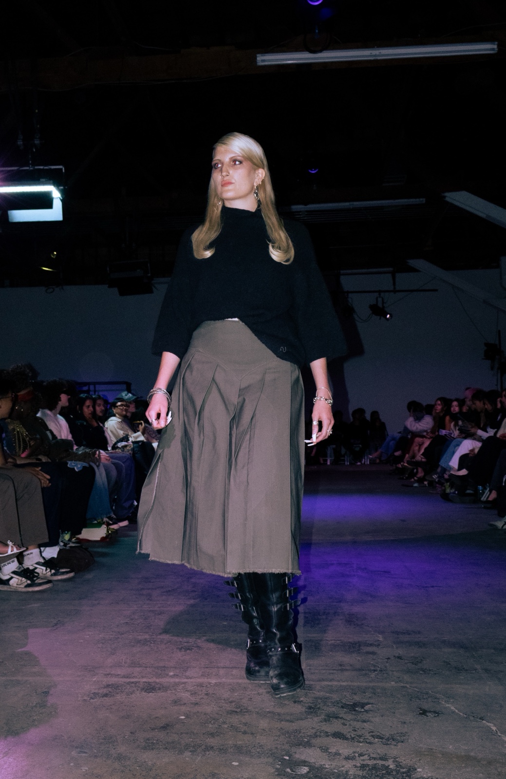Runway — black knit and olive pleated skirt with buckled boots