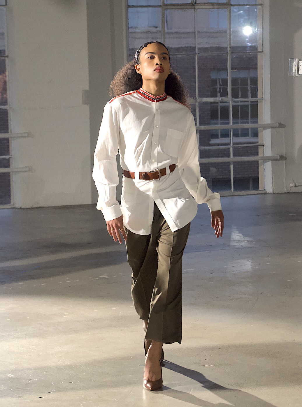White band-collar shirt and olive trousers, walking in daylight
