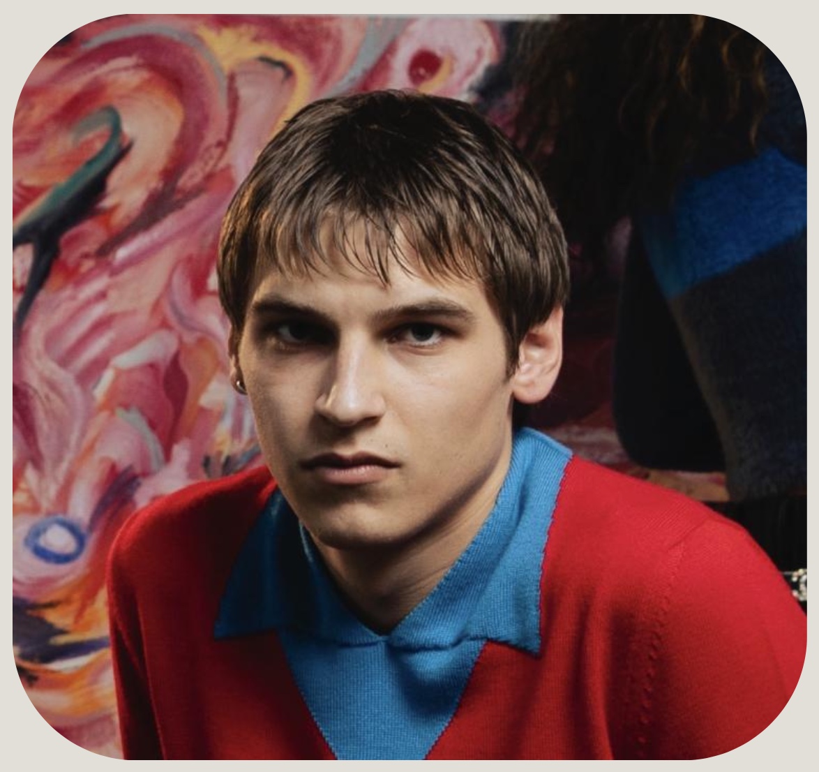The designer, in red, in front of a painting
